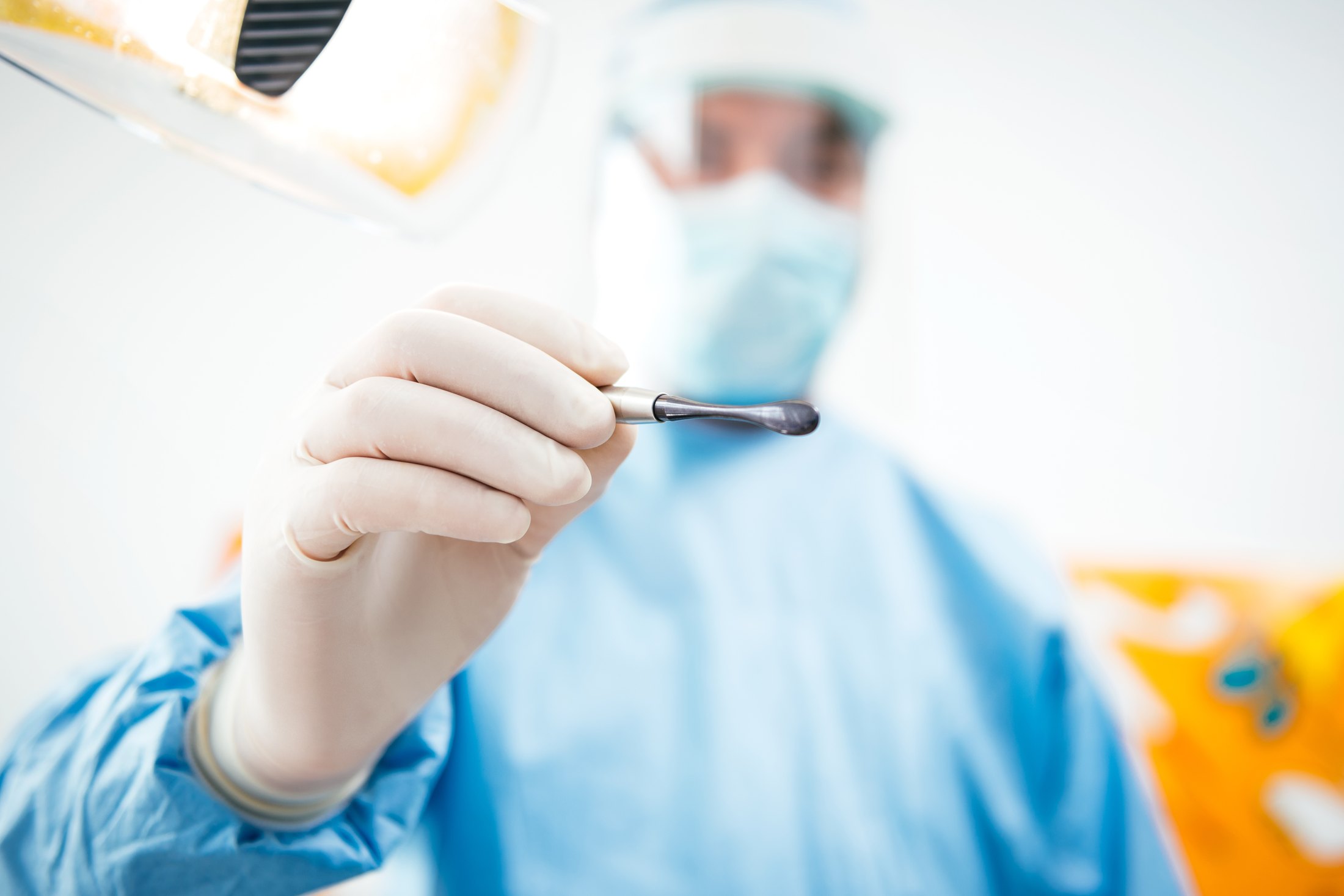 Clinician holding a dental elevator in a surgical setting