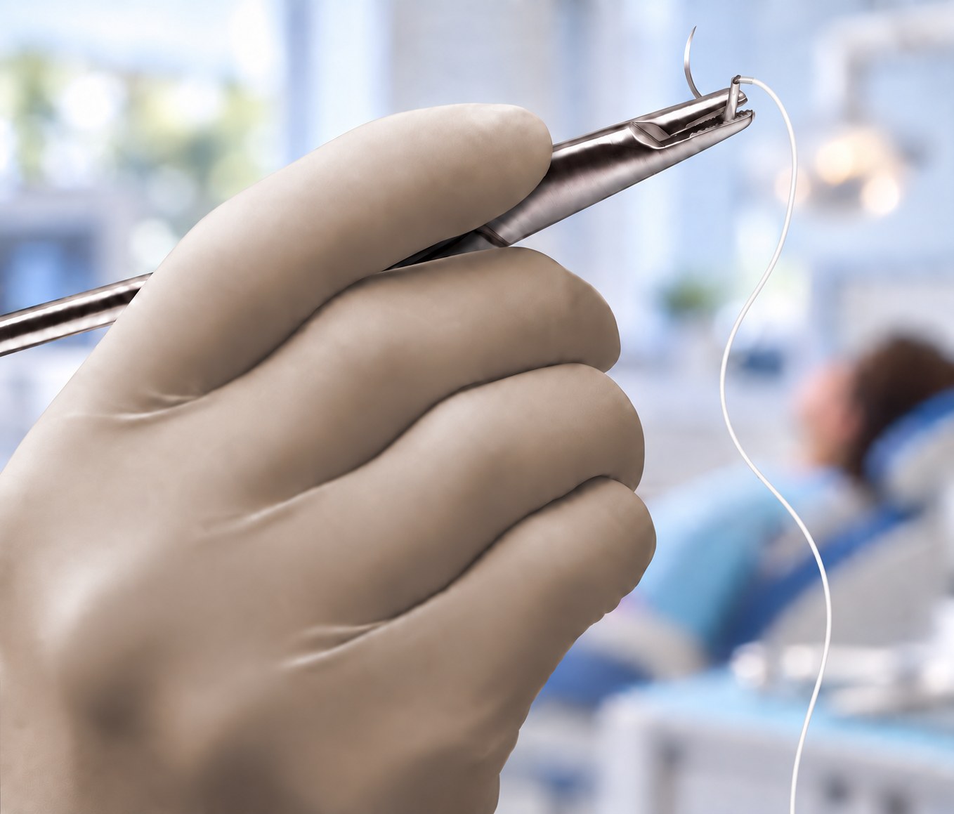 Clinician holding PTFE suture material in a clinical setting